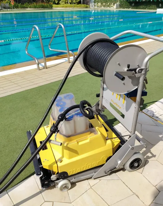 Pool-cleaning machine and hose reel beside a pool