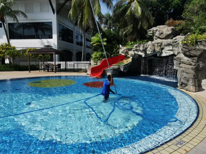 Technician brushing the floor of a swimming pool