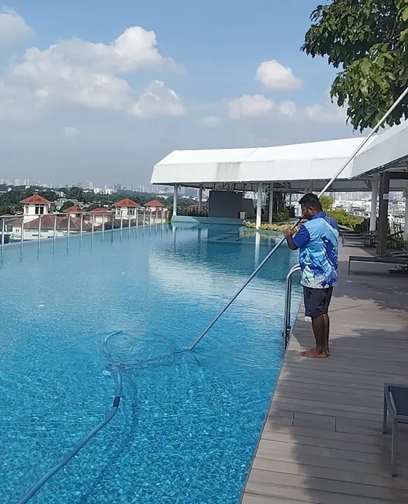 Technician cleaning a large outdoor swimming pool