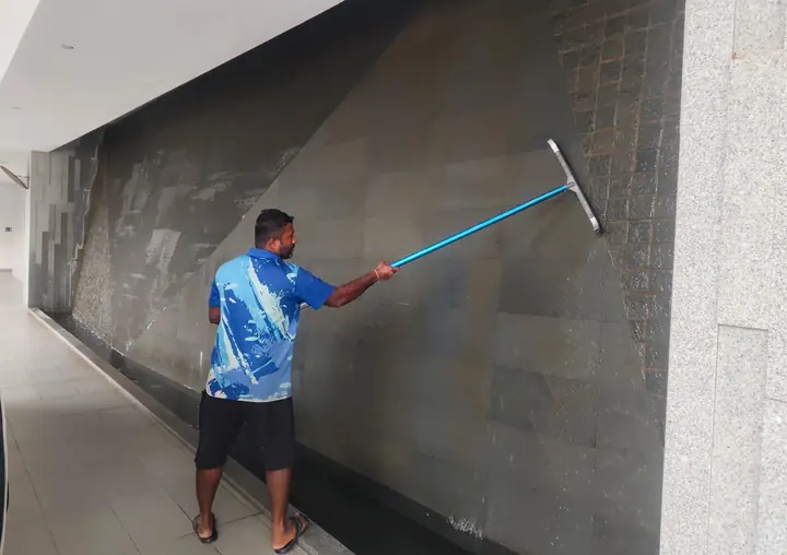 Technician washing a large tiled wall