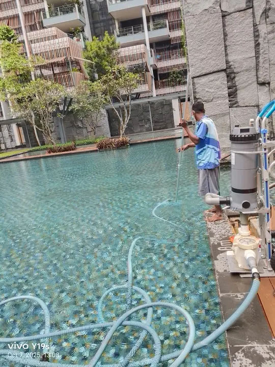 Technician cleaning the edge of an outdoor pool