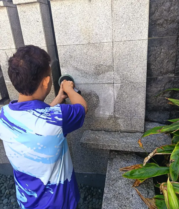 Technician washing a textured tiled wall