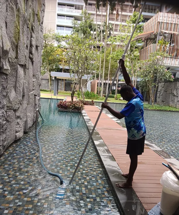 Technician cleaning a curved outdoor pool