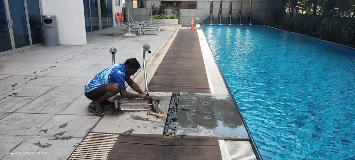 Technician cleaning the channel beside a swimming pool