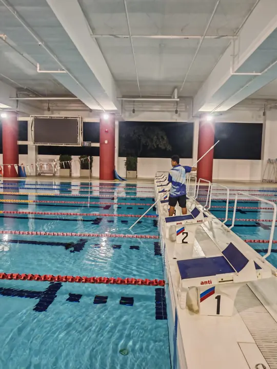 Technician cleaning an indoor competition pool