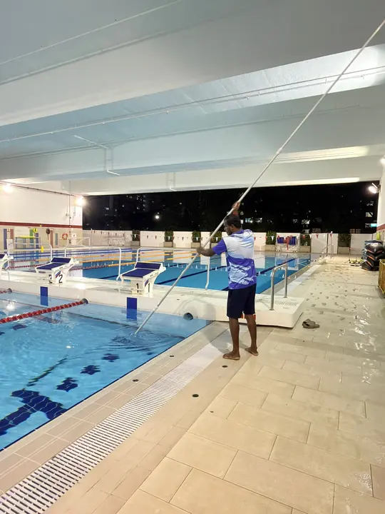 Technician cleaning the deck beside an indoor pool