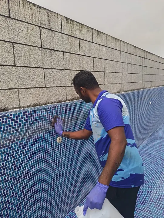 Technician applying repair material to pool wall tiles