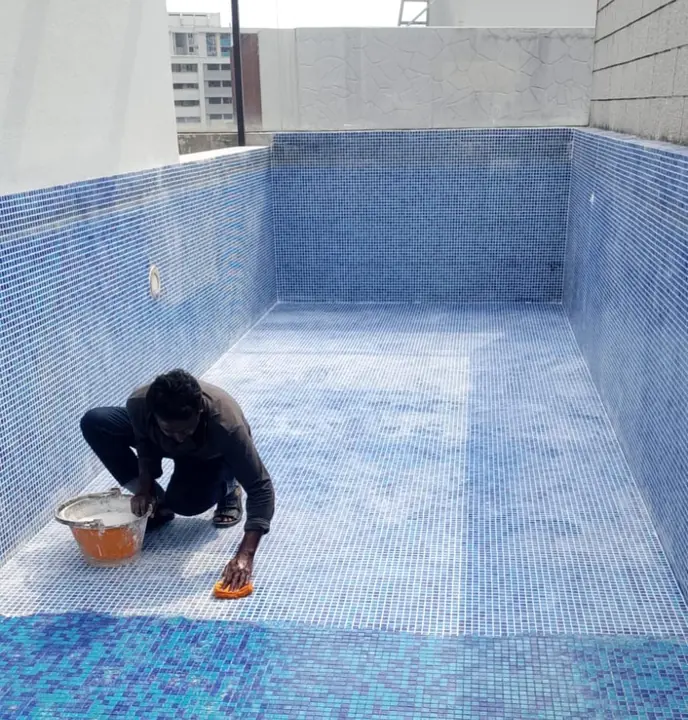 Technician working on tiles inside an emptied pool