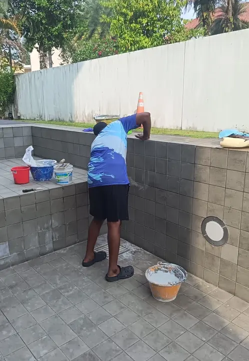 Technician applying material to an empty pool wall