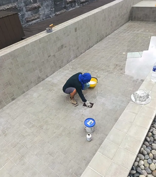 Technician completing repairs on an empty tiled pool floor