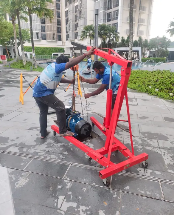 Technicians lifting a pump with a portable hoist