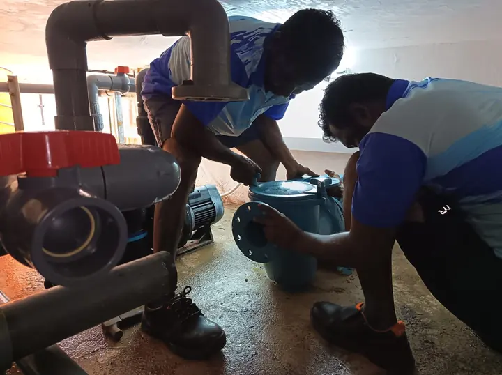 Technicians dismantling pool pump pipework