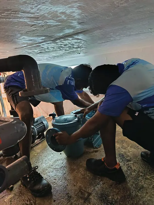 Two technicians repairing a pool pump assembly