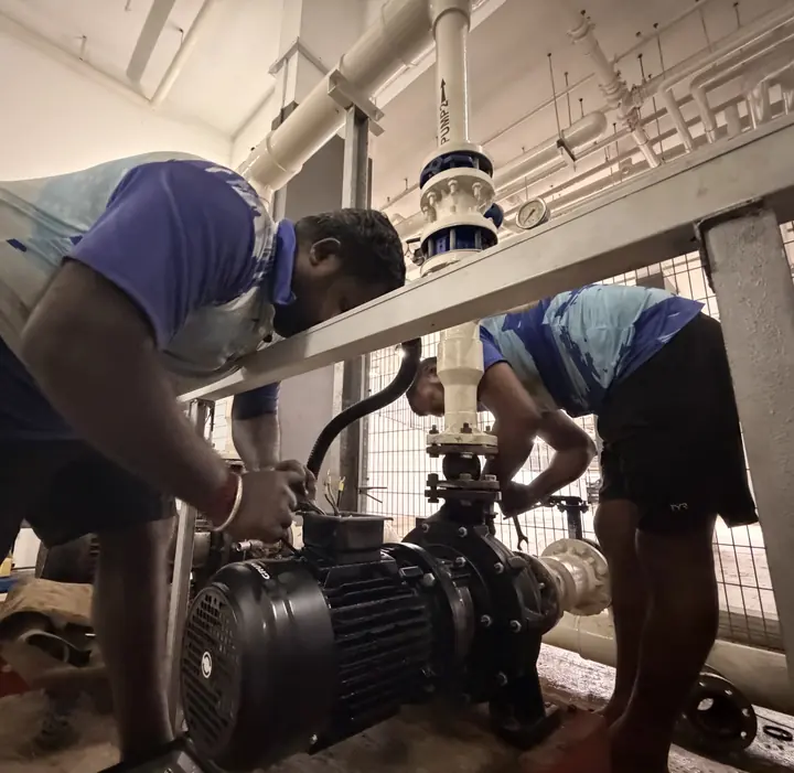 Technicians repairing a pool pump in a plant room