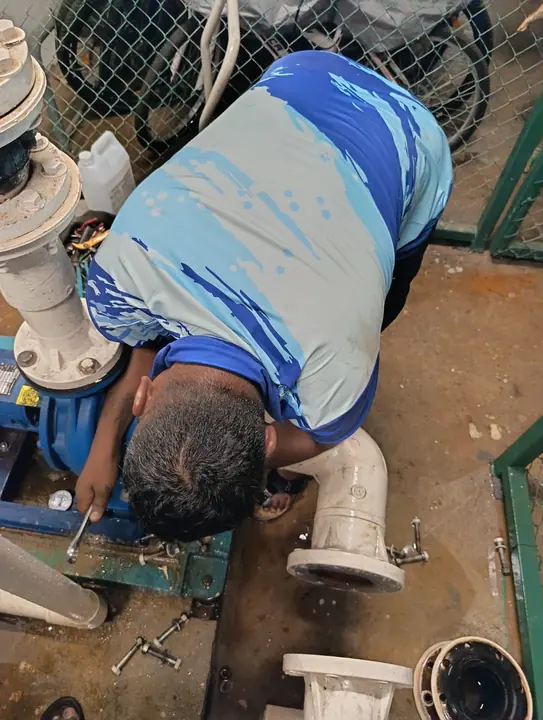 Technician carrying out pump maintenance in an equipment area