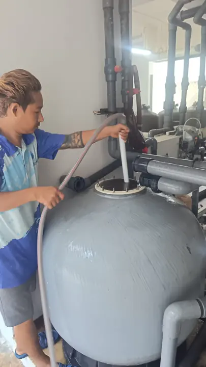 Technician servicing the top of a water treatment vessel